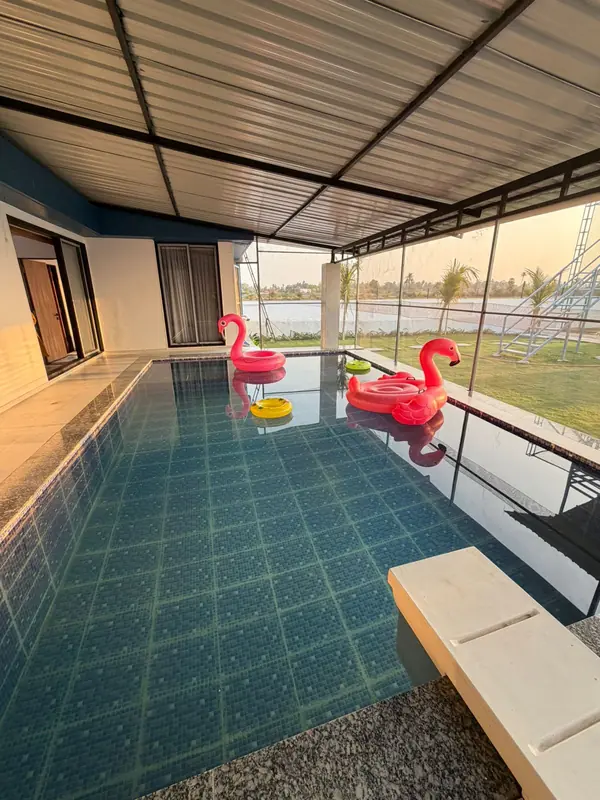 Covered private swimming pool with paved deck at Green Vibes Villa, Olpad
